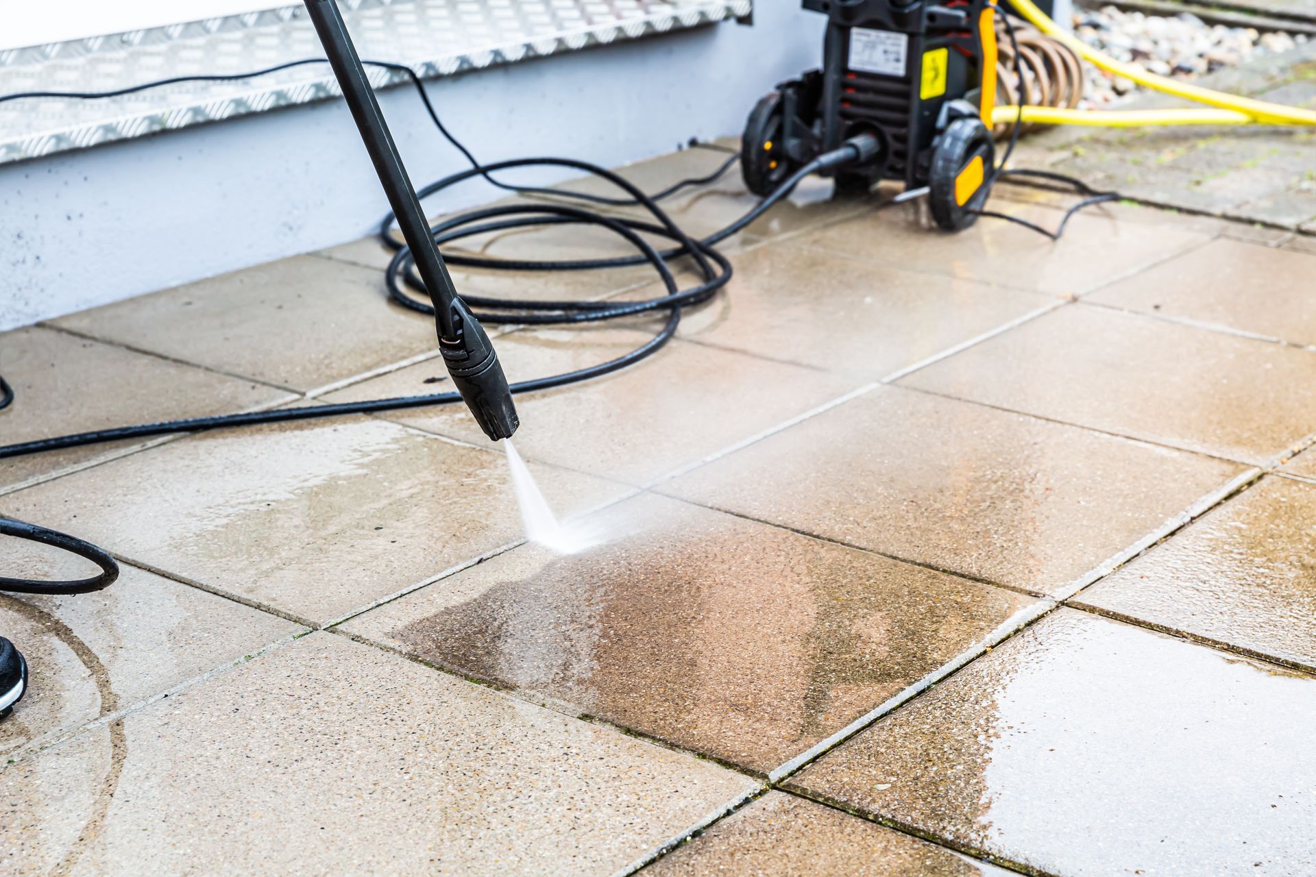 Nettoyage d'une terrasse carrelée avec un nettoyeur à haute pression.
