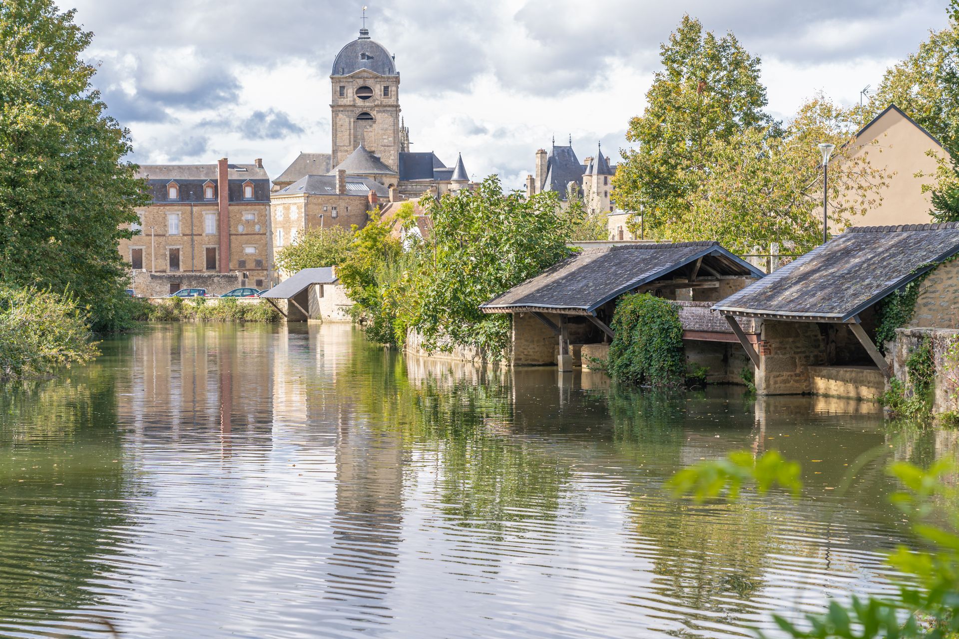 Des bâtiments et le clocher d'une église se reflète dans l'eau.