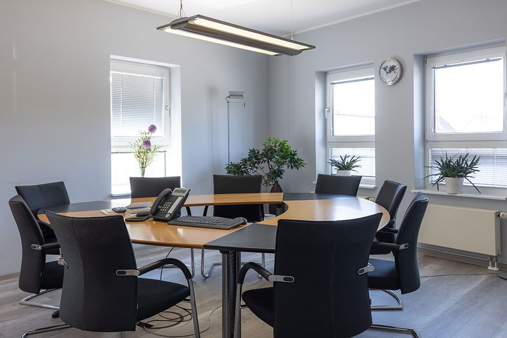 Ein Konferenzraum mit einem runden Tisch und Stühlen und einer Uhr an der Wand.