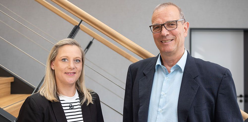 Ein Mann und eine Frau stehen nebeneinander vor einer Treppe.