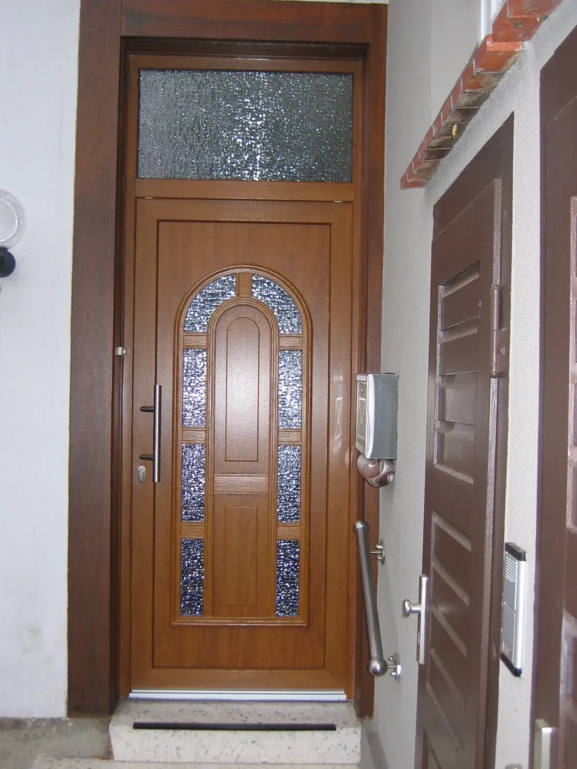 Braune Tür mit Glaseinsätzen und Oberlicht.