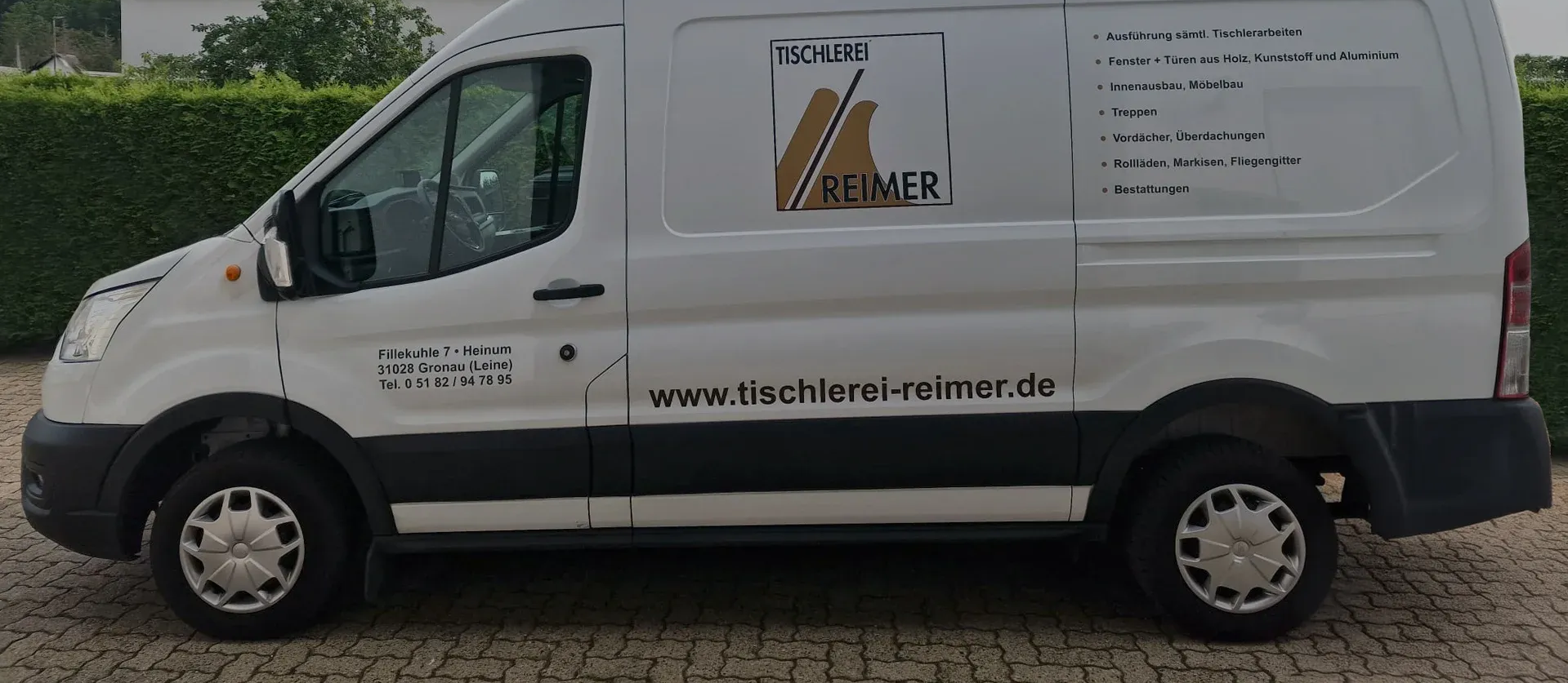 Ein weißer Lieferwagen mit Firmenlogo steht auf einem gepflasterten Platz. Die Website-Adresse ist sichtbar.