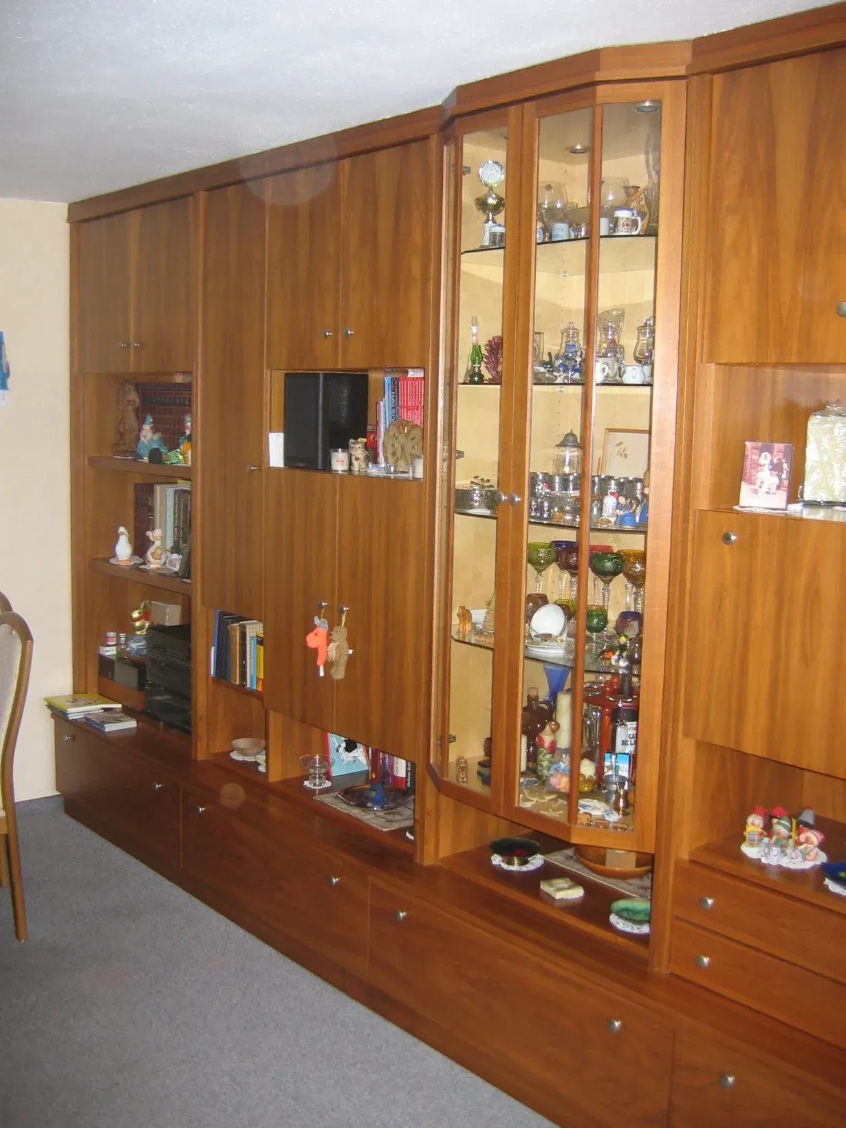 Holzwandschrank mit Schränken, Vitrine und Schubladen, gefüllt mit verschiedenen Gegenständen.