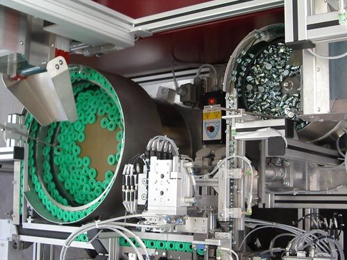 Industrielle Sortiermaschine mit rotierender Trommel voller grüner Bauteile auf Zuführbahn