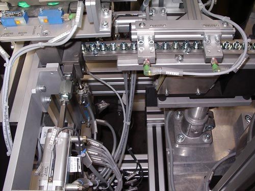 Nahaufnahme Industriemaschine mit metallischen Bauteilen, pneumatischen Zylindern, Verkabelung und Schiene