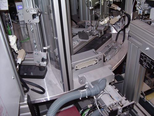 Nahaufnahme einer Industriemaschine mit silbernen Metallrahmen, einem mehrpoligen elektrischen Steckverbinder und Wellrohren.