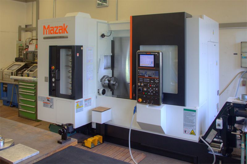 Weiße und schwarze Mazak CNC-Werkzeugmaschine in einer Werkstattumgebung mit einem Bedienfeld an der Vorderseite.