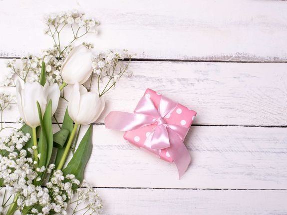 Geschenke Deko Tulpen und Geschenk in pinker Verpackung auf weißem Holzhintergrund