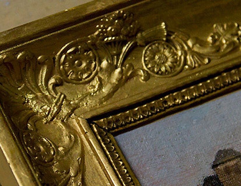 Gros plan sur un coin de cadre photo doré décoratif orné de motifs floraux.