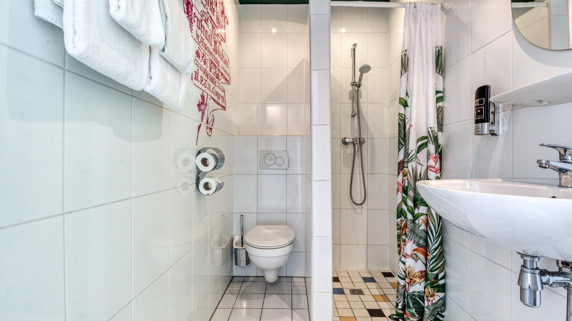 A bathroom with a toilet , sink and shower.