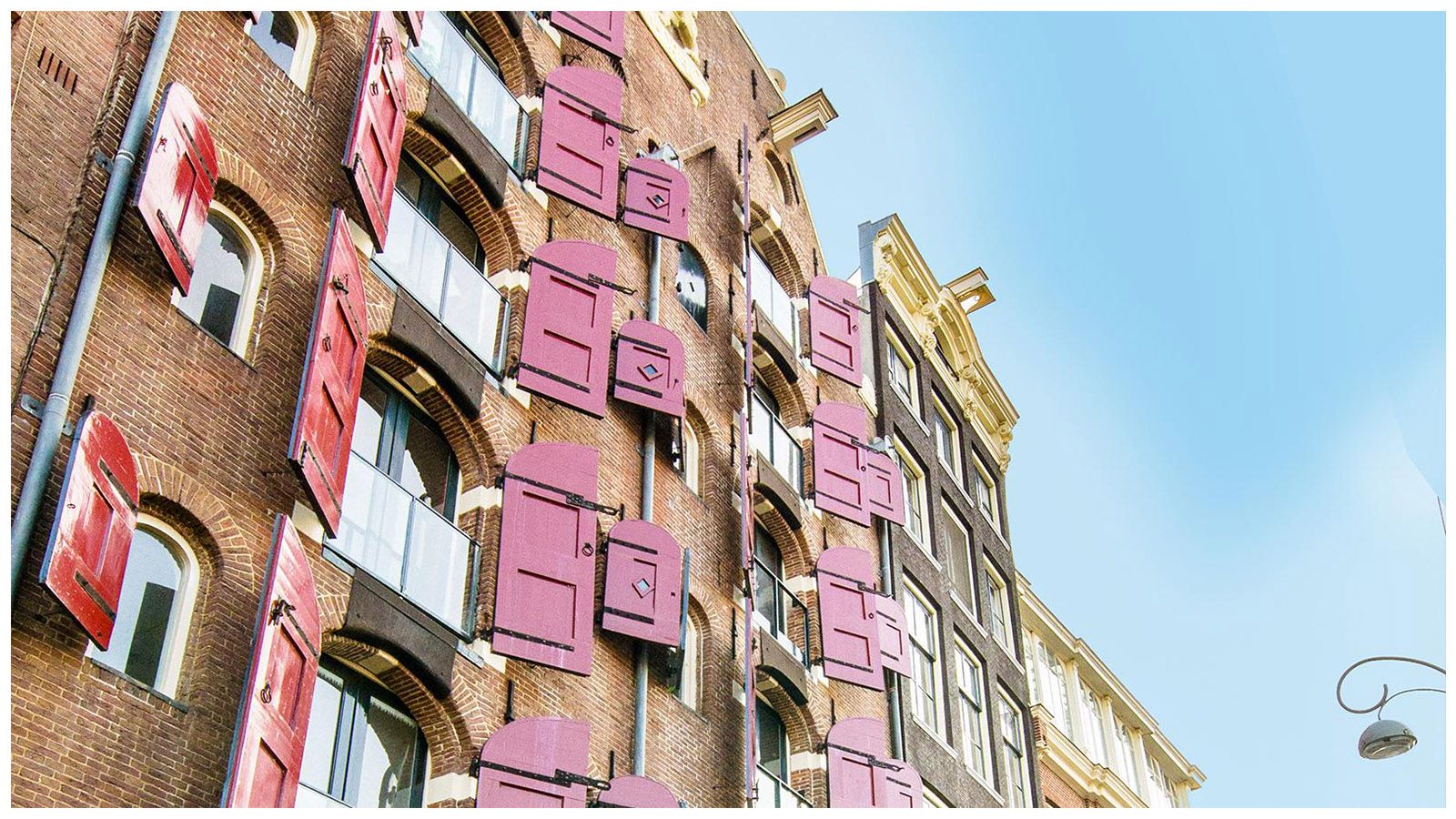 A brick building with pink shutters on the windows