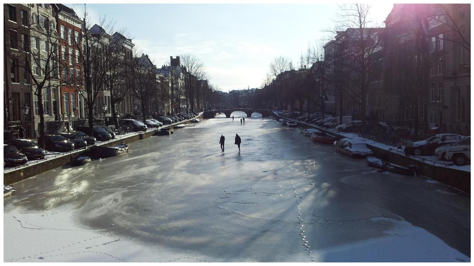 Two people are ice skating on a frozen river