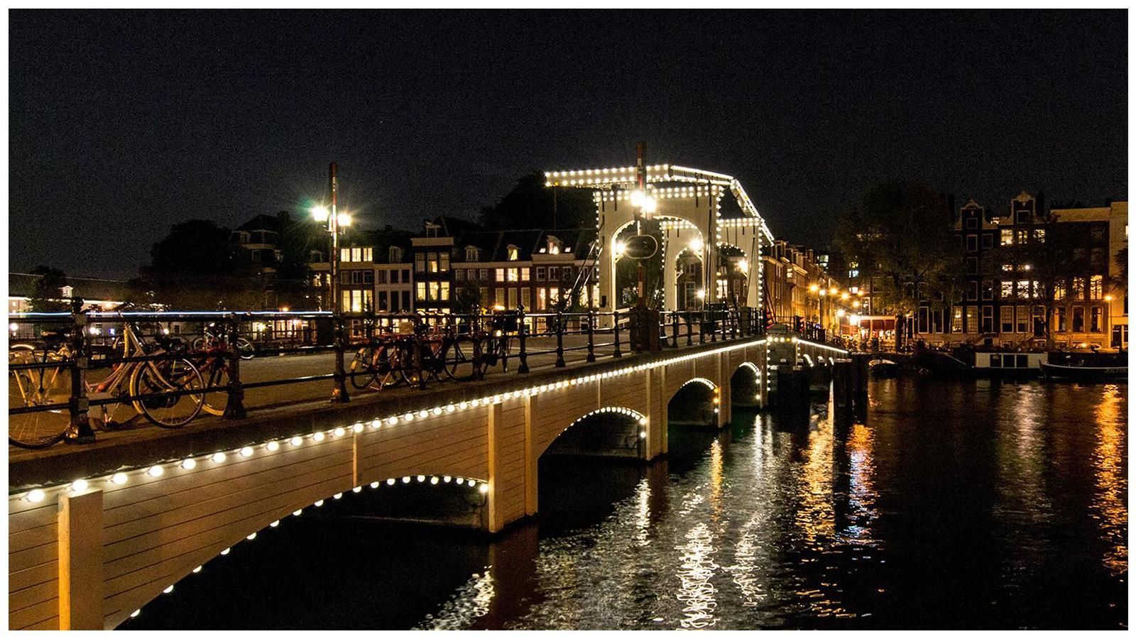 A bridge over a body of water is lit up at night