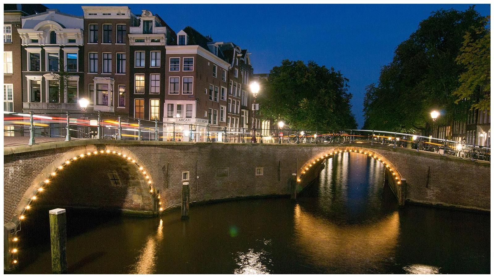 A bridge over a river is lit up at night