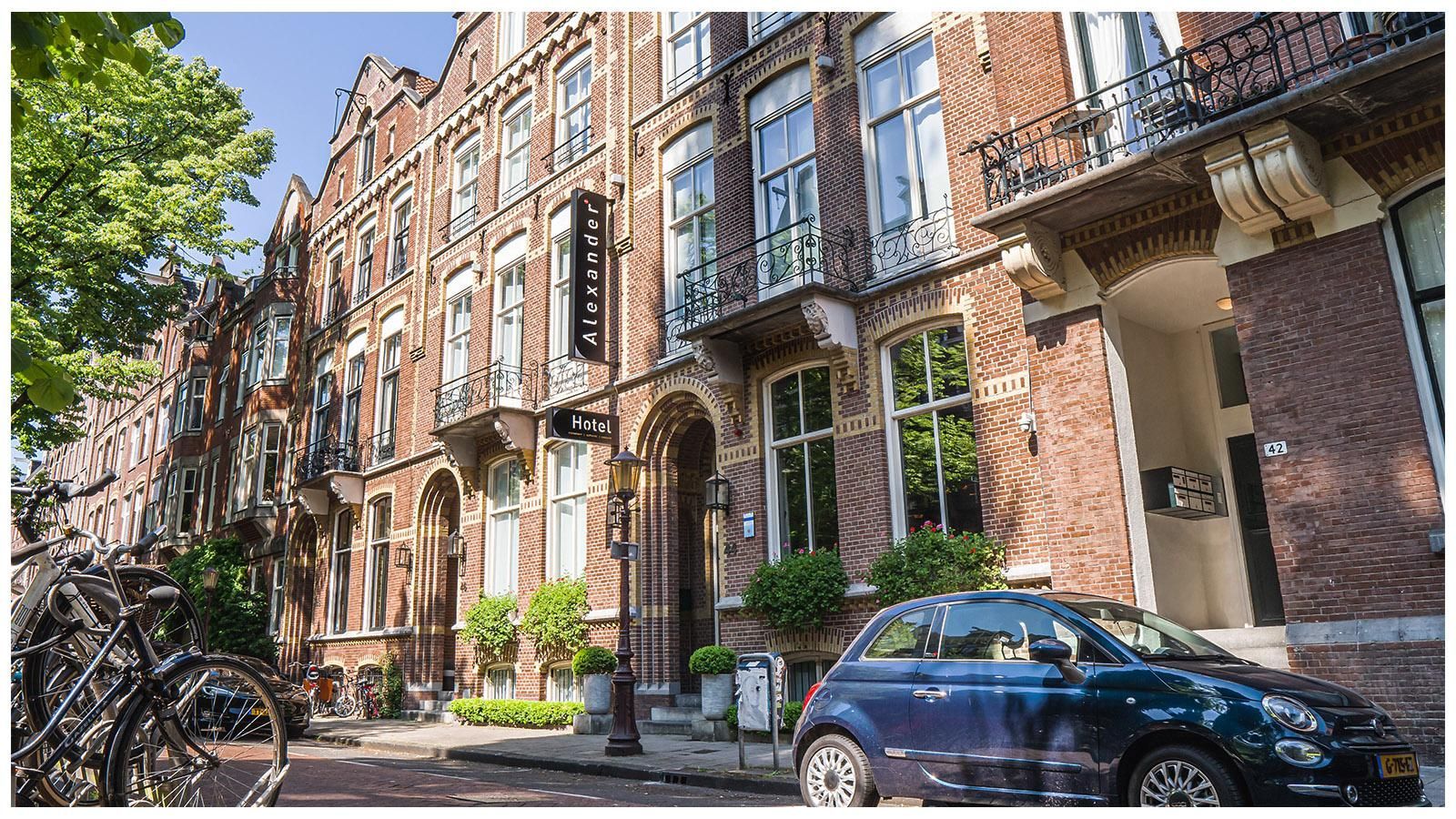 A blue car is parked in front of a brick building.