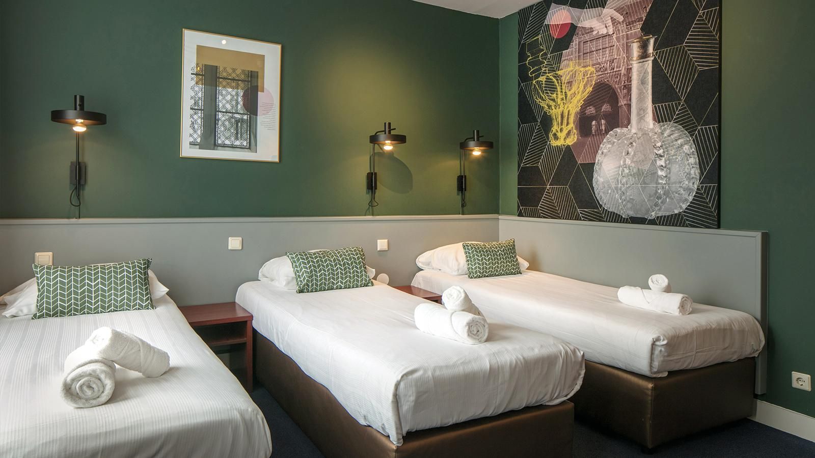 Ein Hotelzimmer mit drei Betten und einem Gemälde an der Wand.