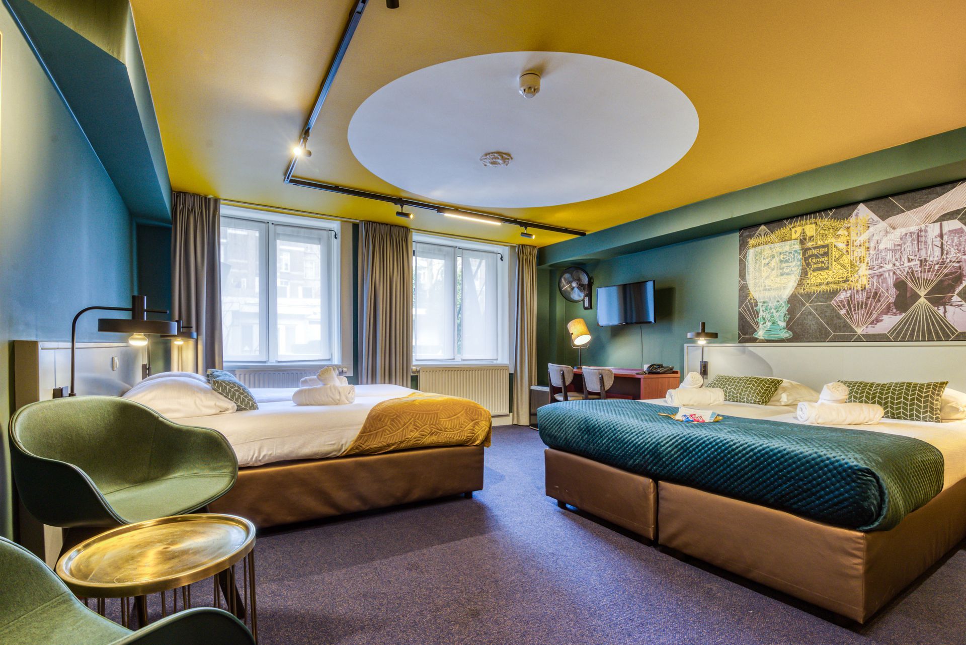 Spacious room with a yellow ceiling and two beds with gold and teal bedspreads