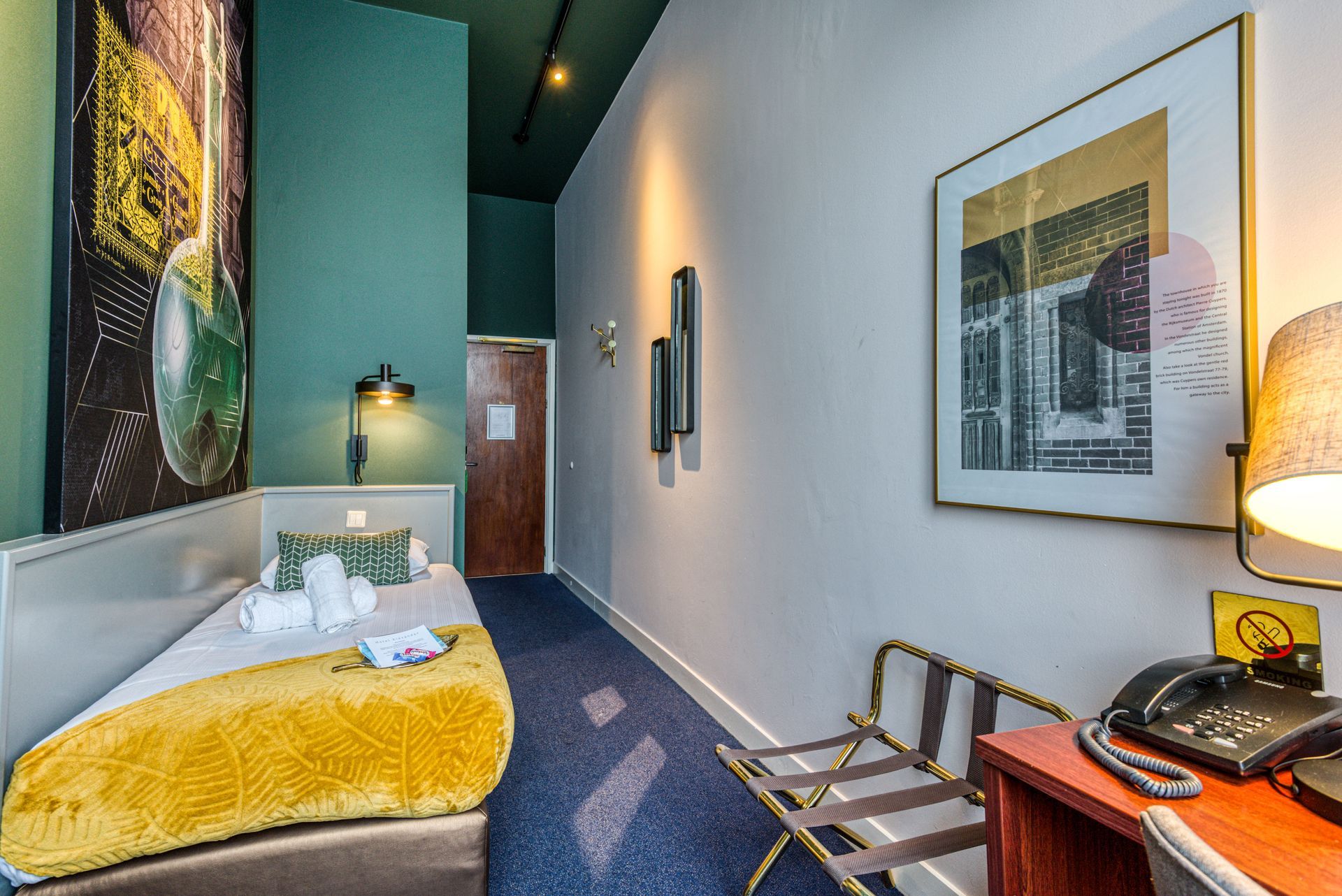 Double room at Hotel Alexander with a mustard-yellow bedspread, green walls and framed artwork
