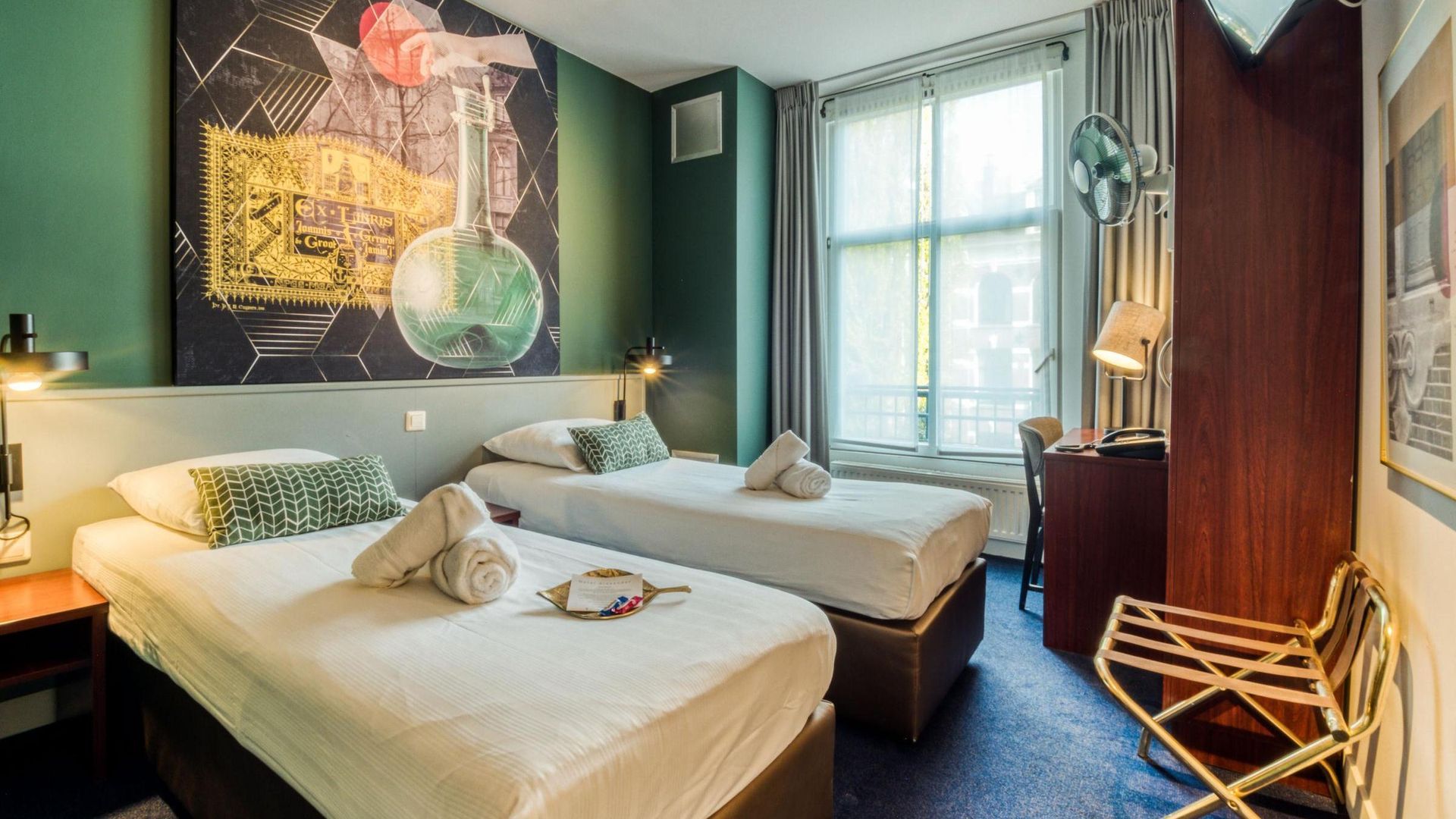 A hotel room with two beds and a painting on the wall.