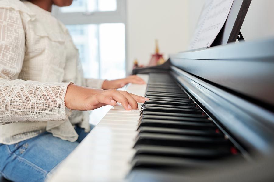 Une personne jouant du piano, les mains sur les touches, une partition en arrière-plan.