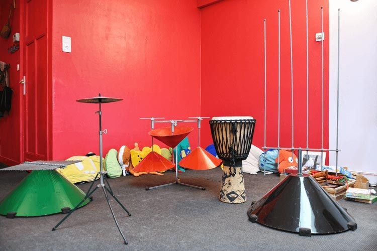 Salle de musique avec mur rouge, batterie et sculptures métalliques.