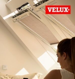 Una mujer mira hacia un tragaluz con un logotipo de Velux en la esquina.