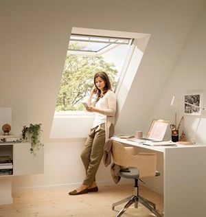 Una mujer está parada frente a una ventana en una habitación.