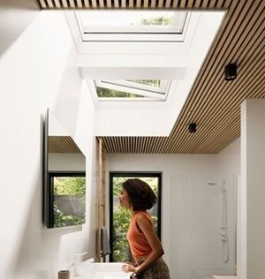 Una mujer está parada en un baño mirando hacia el tragaluz.