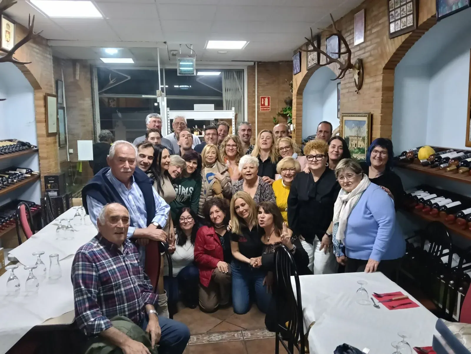 Un numeroso grupo de personas sonríe y posa para una foto dentro de un restaurante 