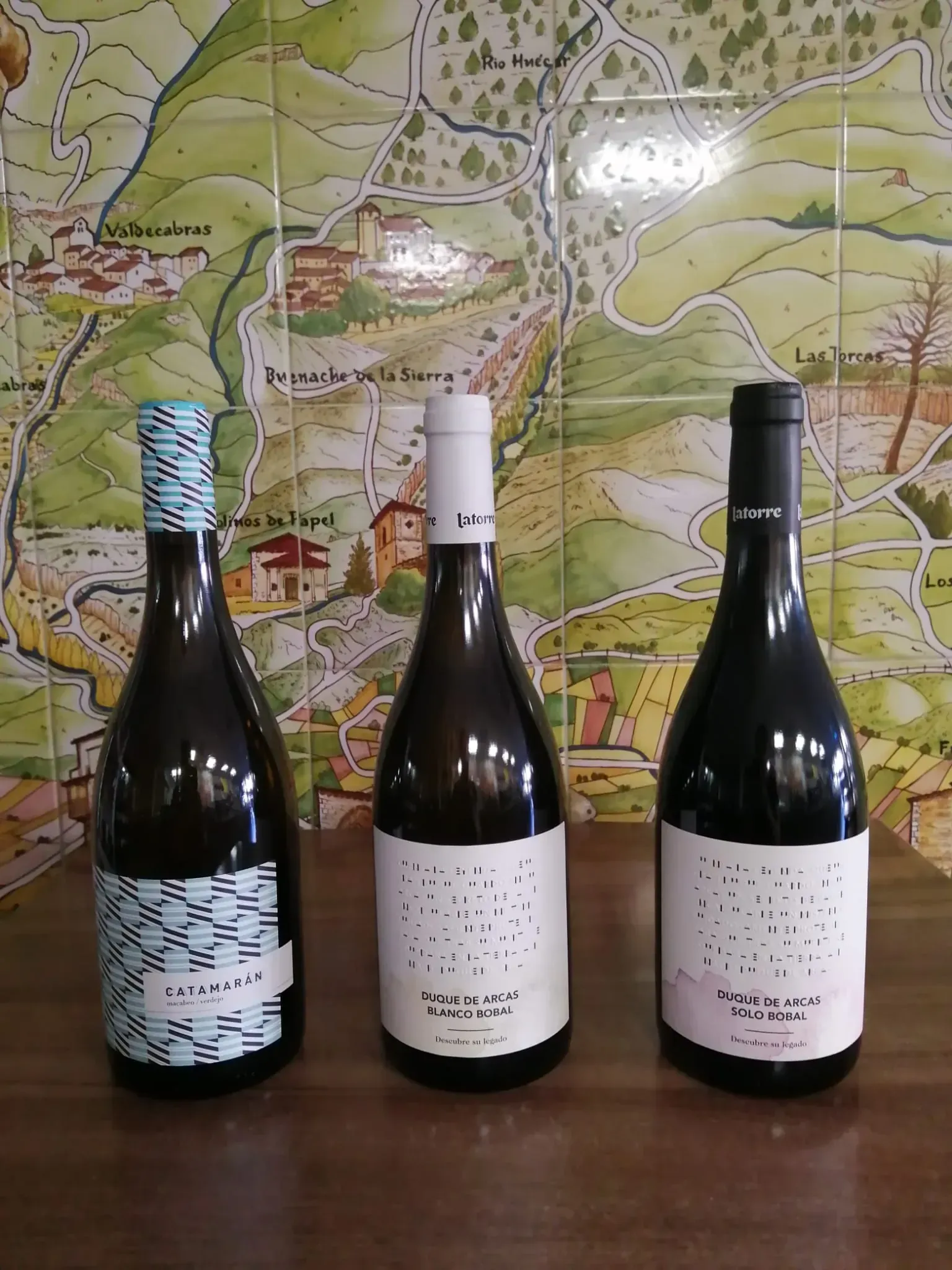 Tres botellas de vino con etiquetas gráficas únicas se exhiben sobre una superficie de madera