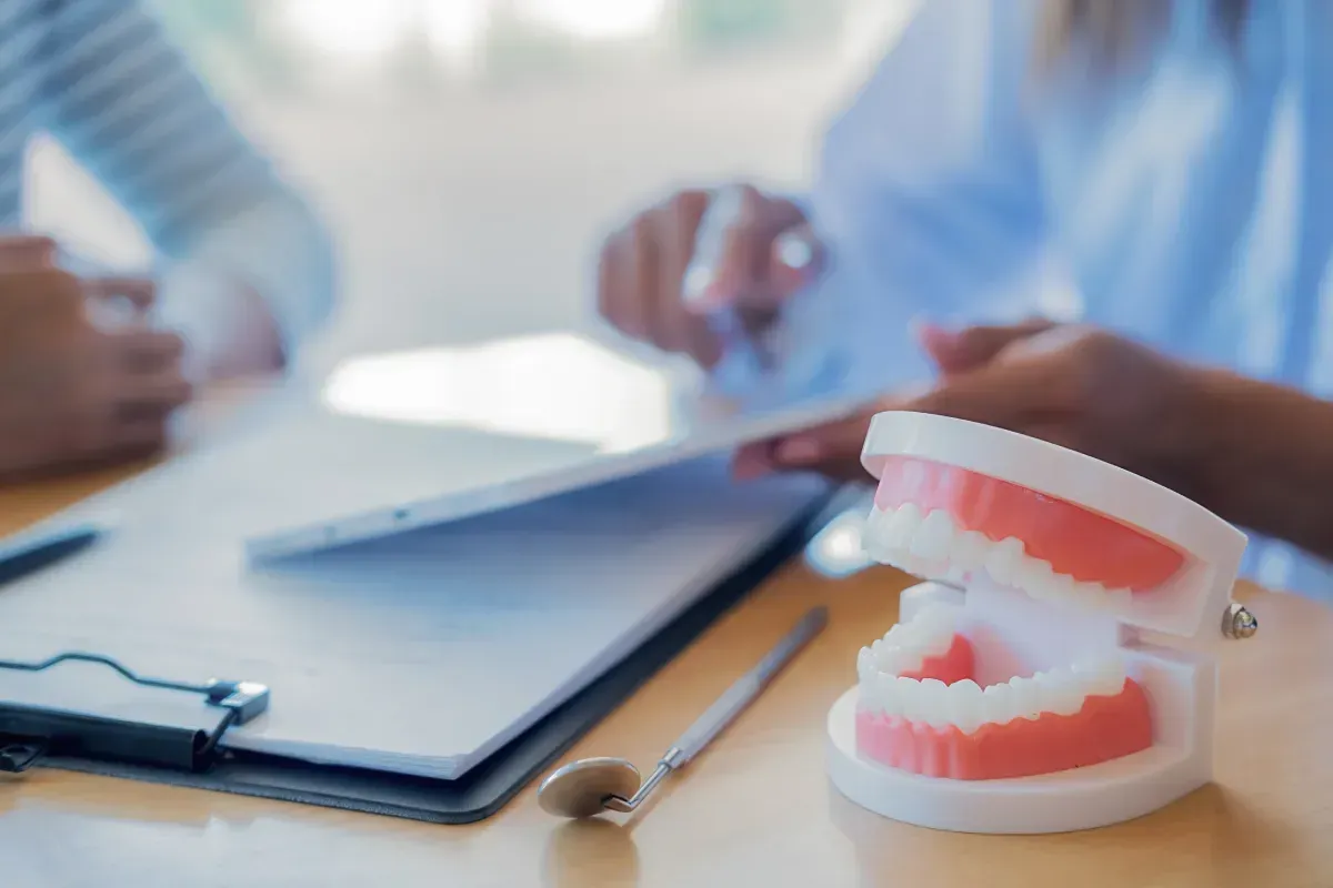 Modelo dental y herramientas sobre una mesa durante una consulta.
