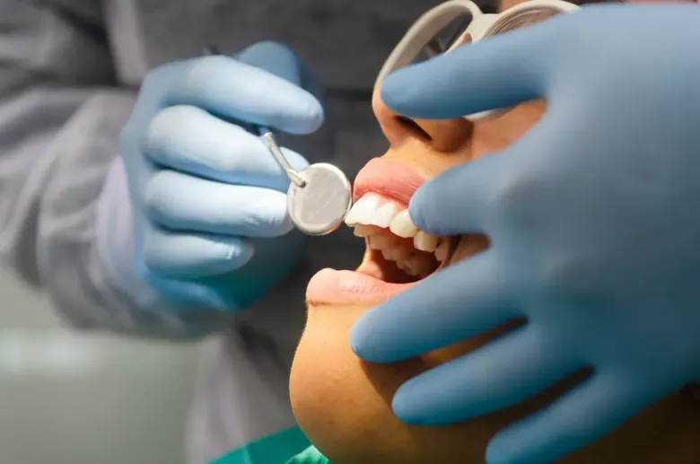 Dentista examinando los dientes de un paciente con un espejo y una sonda.