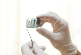 Manos enguantadas de un dentista sosteniendo una radiografía dental y una sonda dental.
