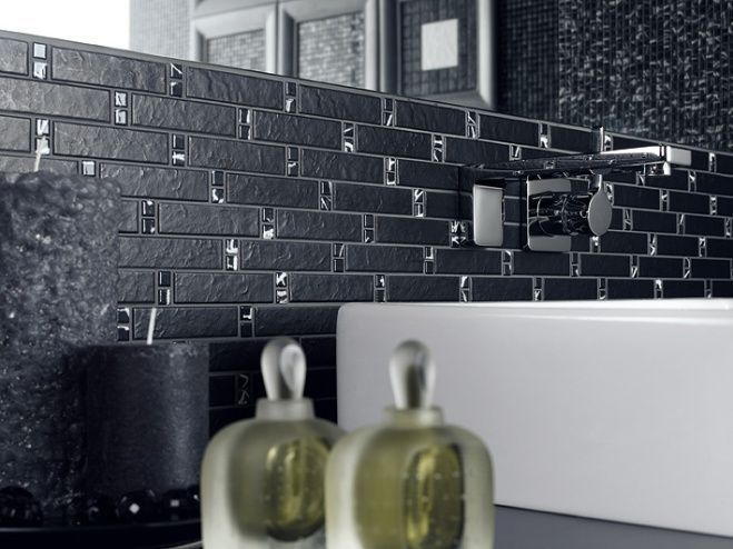 Modernes Badezimmerwaschbecken mit schwarzer Fliesenrückwand und zwei Seifenspendern aus Glas.