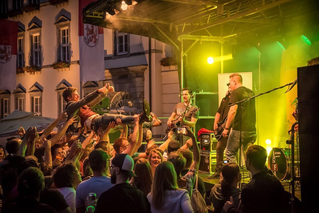 Eine Menschenmenge sieht einer Band beim Auftritt auf der Bühne zu.