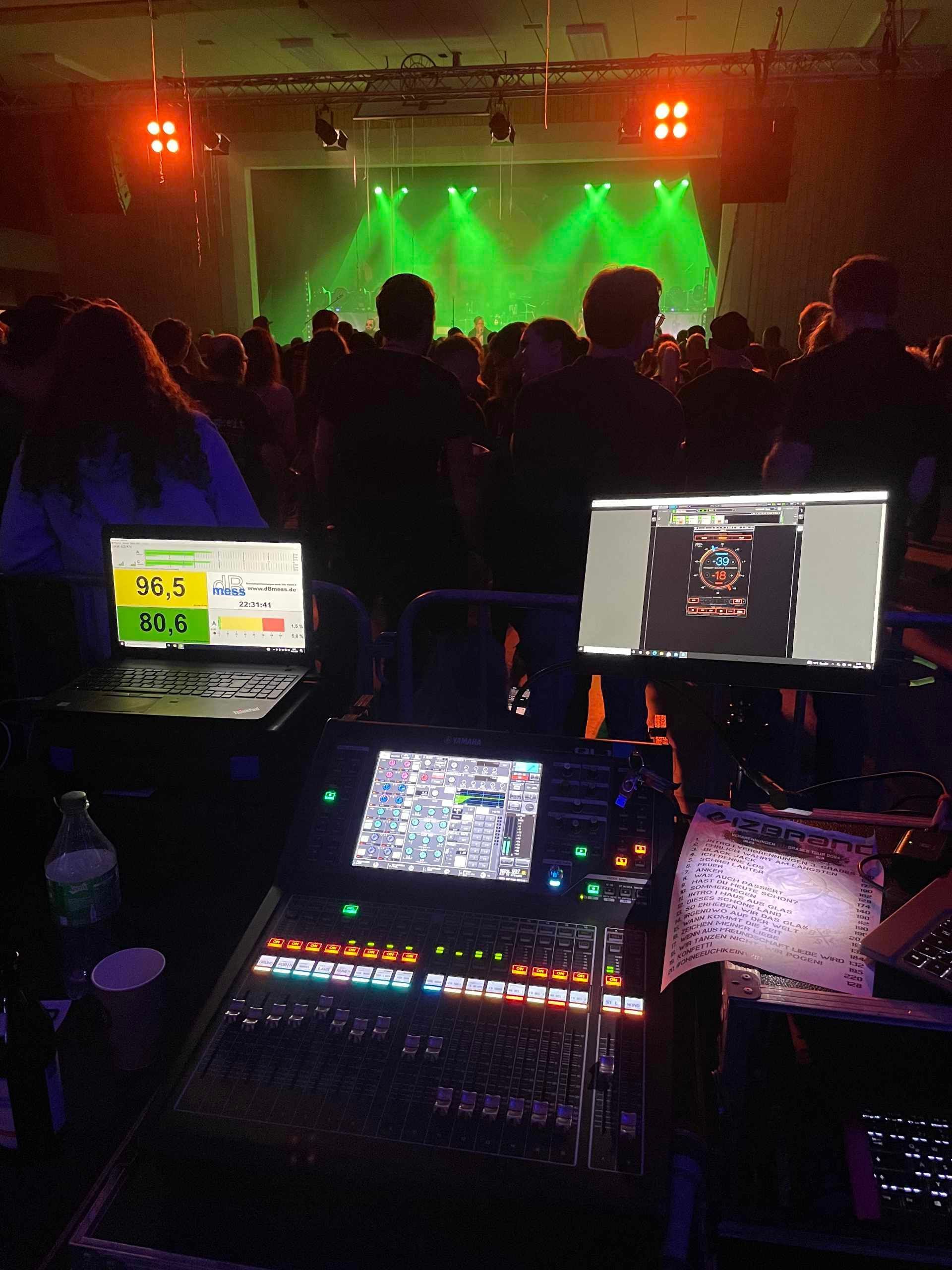 Eine Menschenmenge sitzt vor einer Bühne mit grünem Licht.