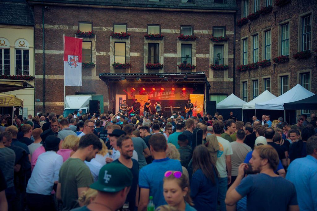 Eine Menschenmenge hat sich vor einer Bühne versammelt, auf der eine Band spielt.