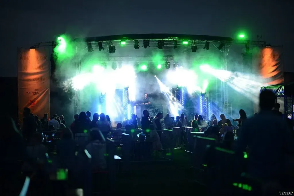 Bei einem Konzert sitzt eine Menschenmenge vor einer Bühne.