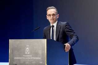 Ein Mann in Anzug und Krawatte steht an einem Podium und hält eine Rede.