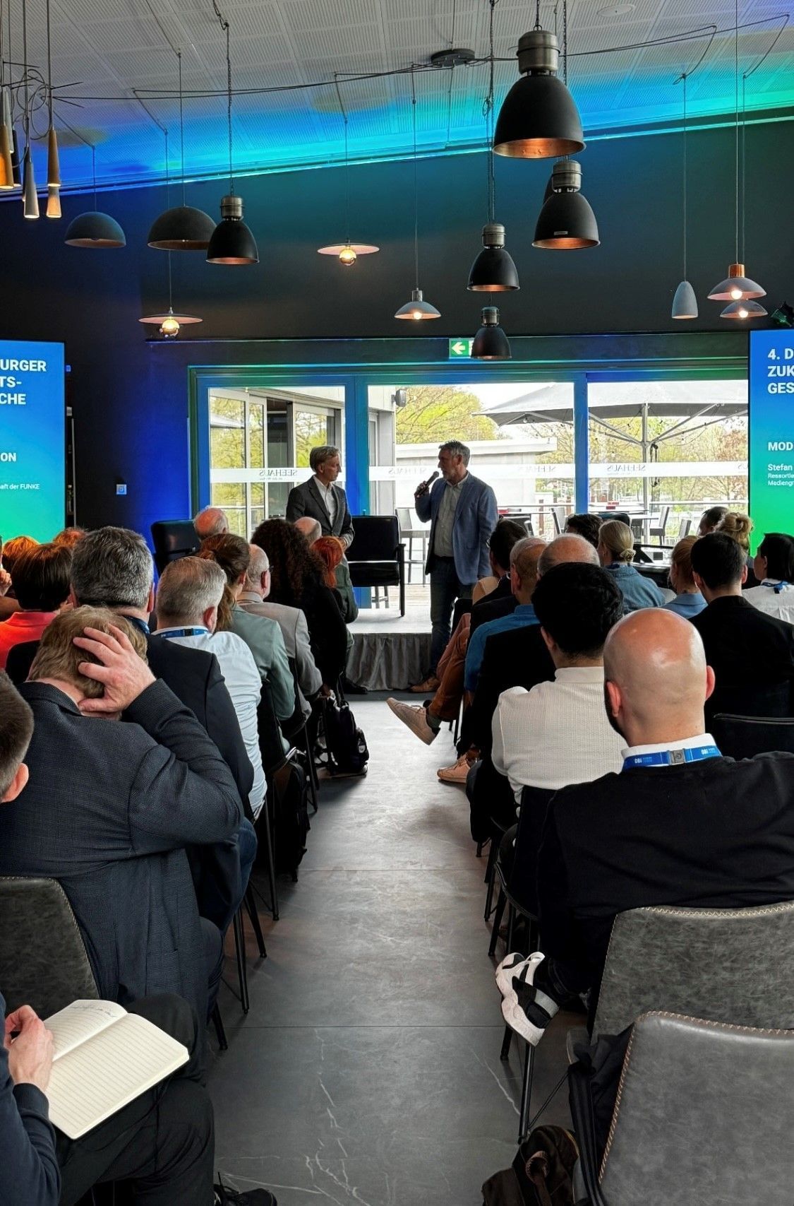 Eine Gruppe von Leuten sitzt in einem Raum und sieht sich eine Präsentation an.