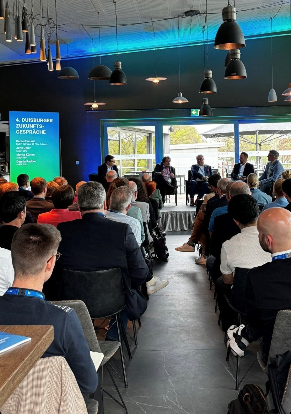 Eine Gruppe von Leuten sitzt in einem Raum und sieht sich eine Präsentation an.