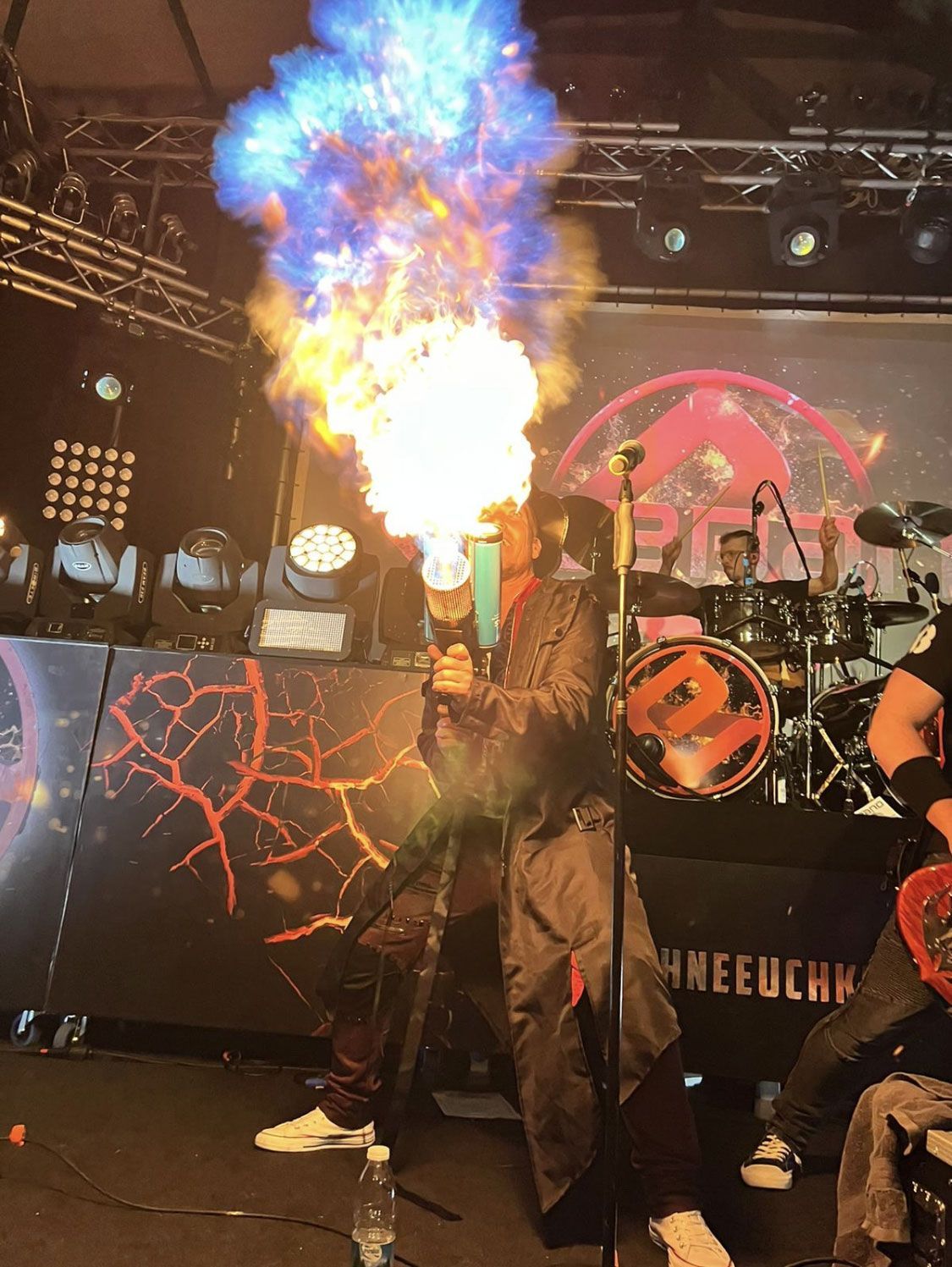 Ein Mann bläst Feuer in ein Mikrofon auf einer Bühne.