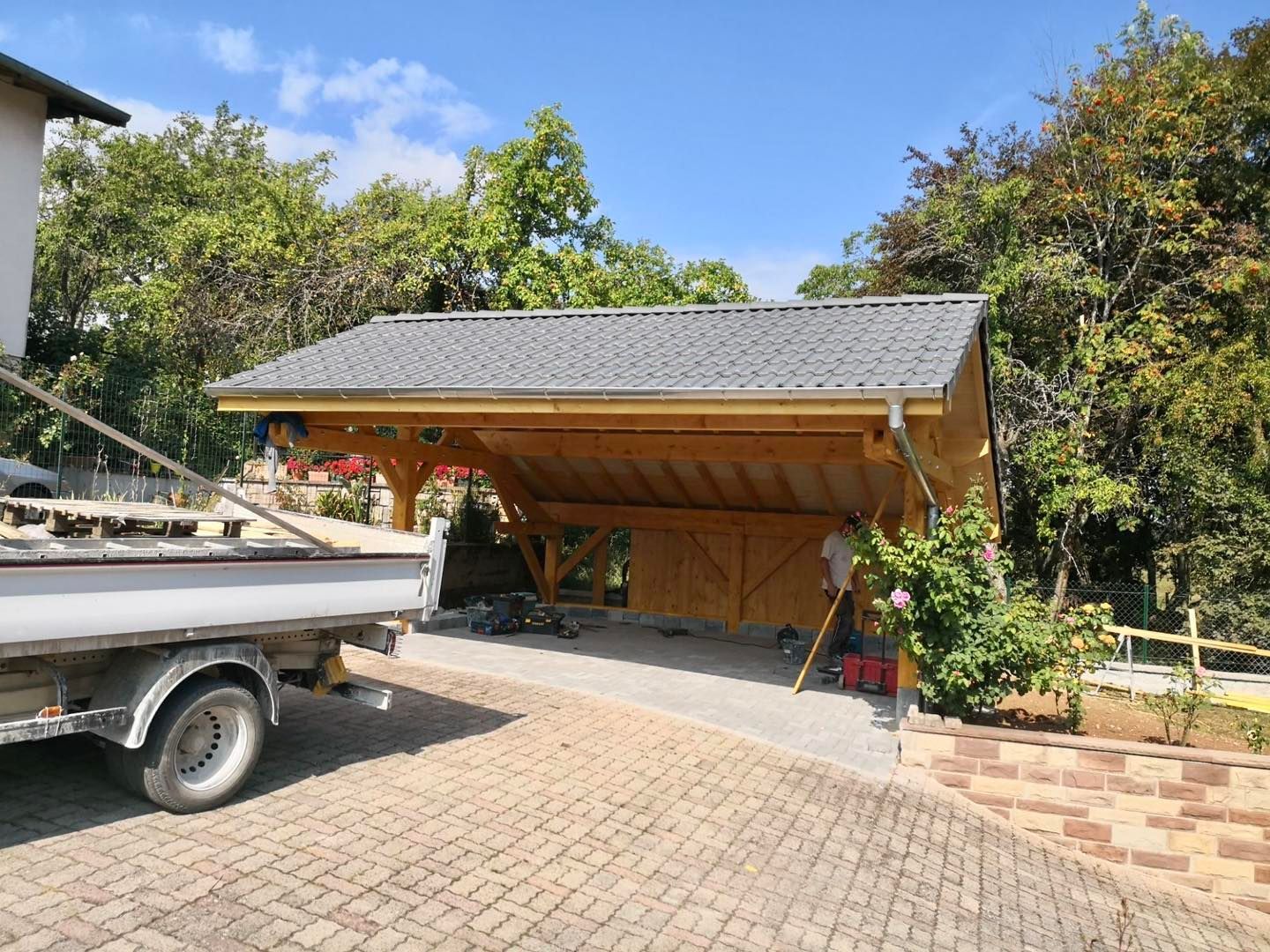 Arrière d'un camion-remorque devant un carport en bois.