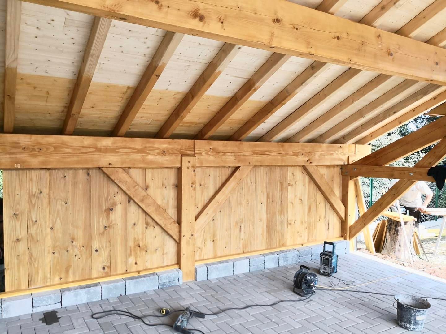 Dessous d'un carport en bois dont le sol est pavé.