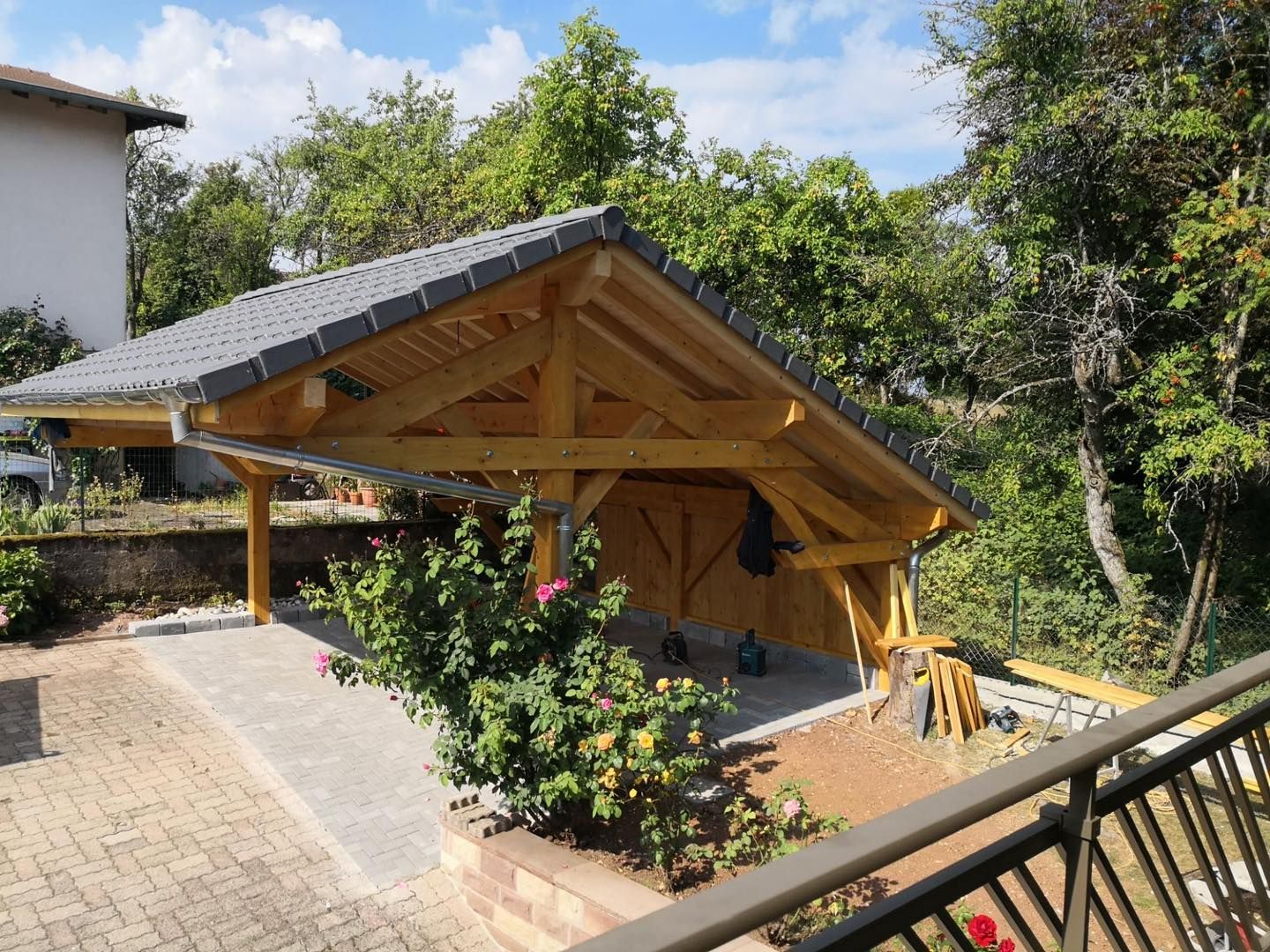 Un carport en bois pour véhicule avec toiture en deux pentes.