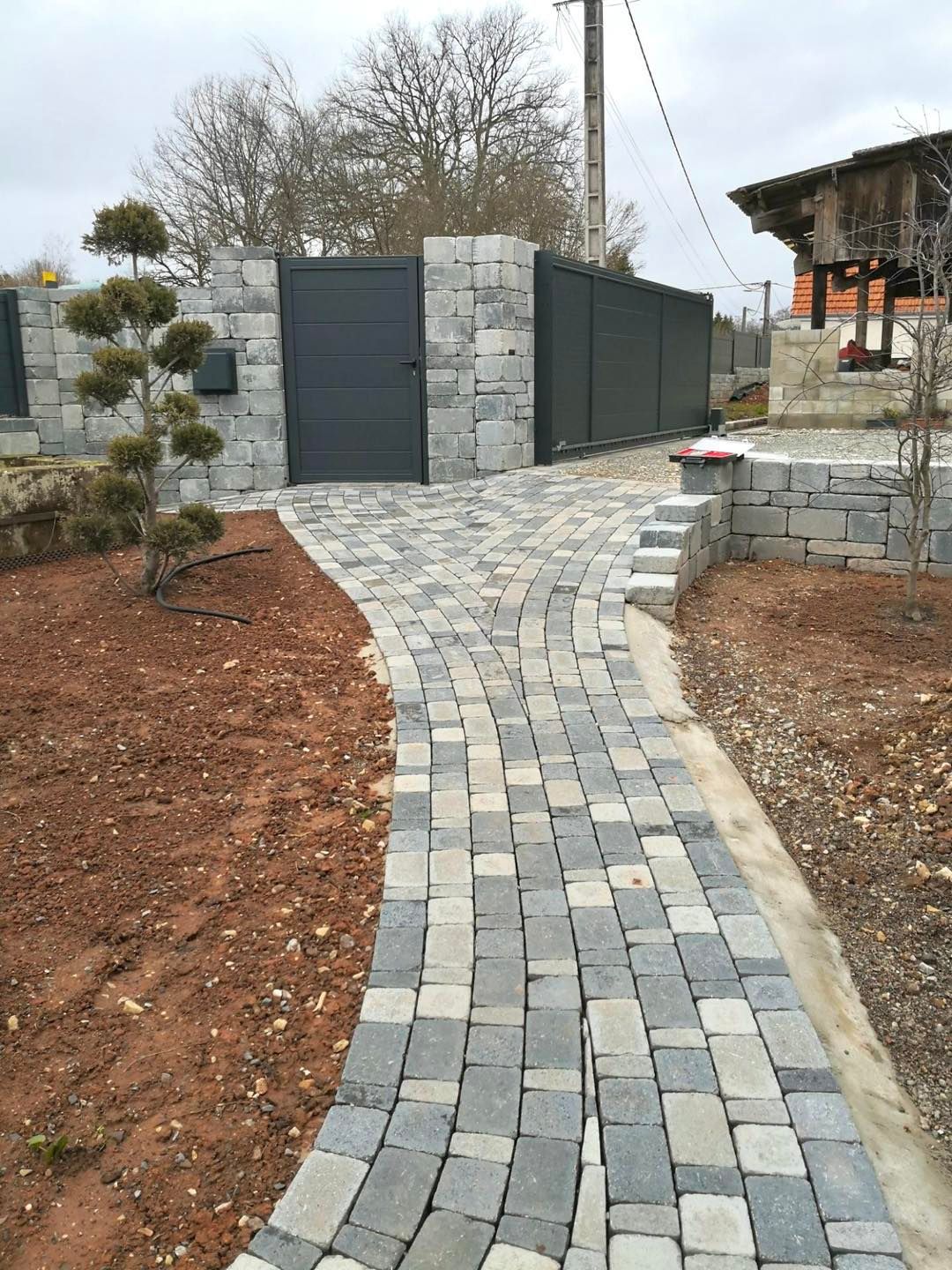 Une allée en dalle de pierre menant vers un portillon.
