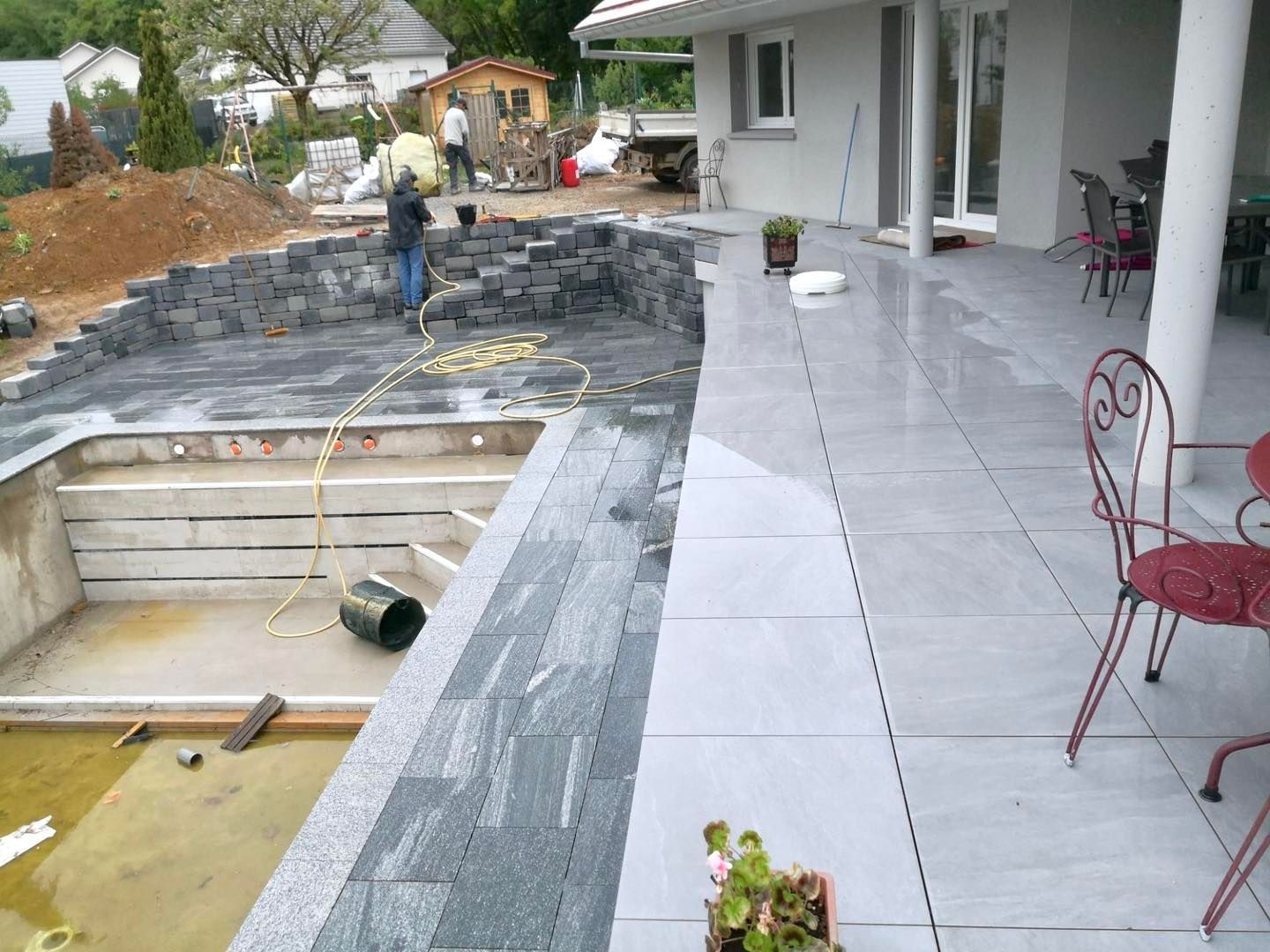 Construction en cours d'une piscine dont le contour est entièrement dallé.