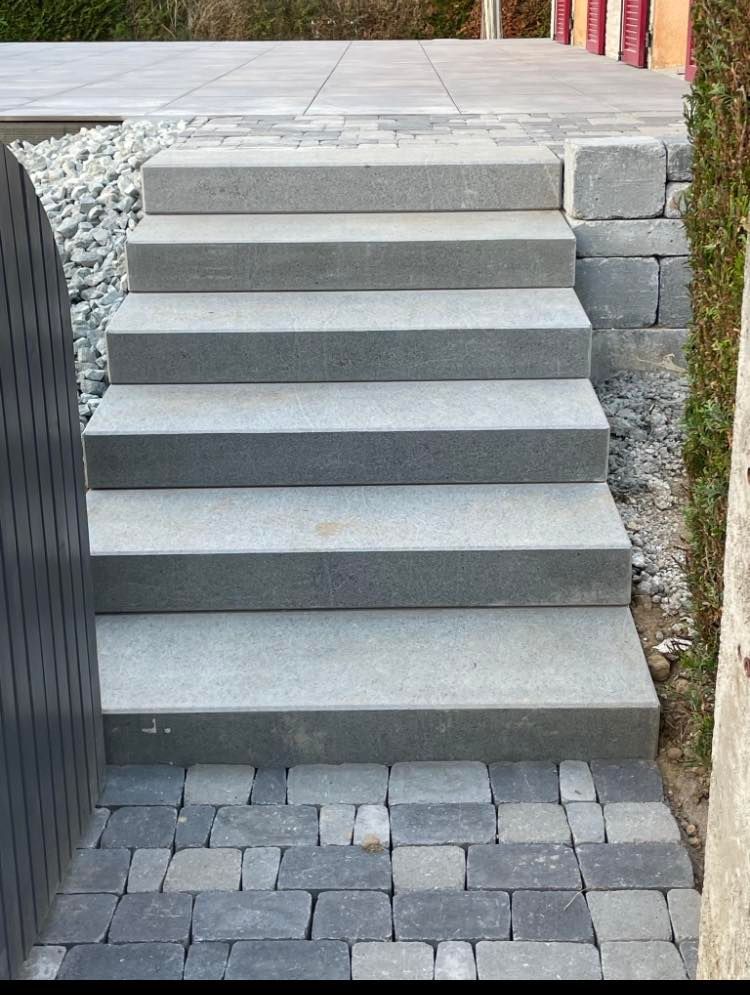 Escalier en béton derrière un portillon ouvert.