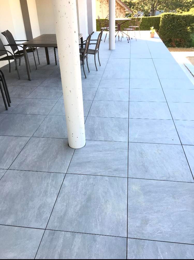 Gros plan sur les dalles d'une terrasse extérieure à proximité d'un poteau.