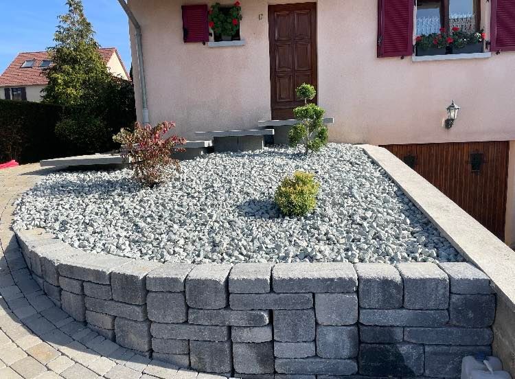 Emplacement pour petits arbustes rempli de cailloux.